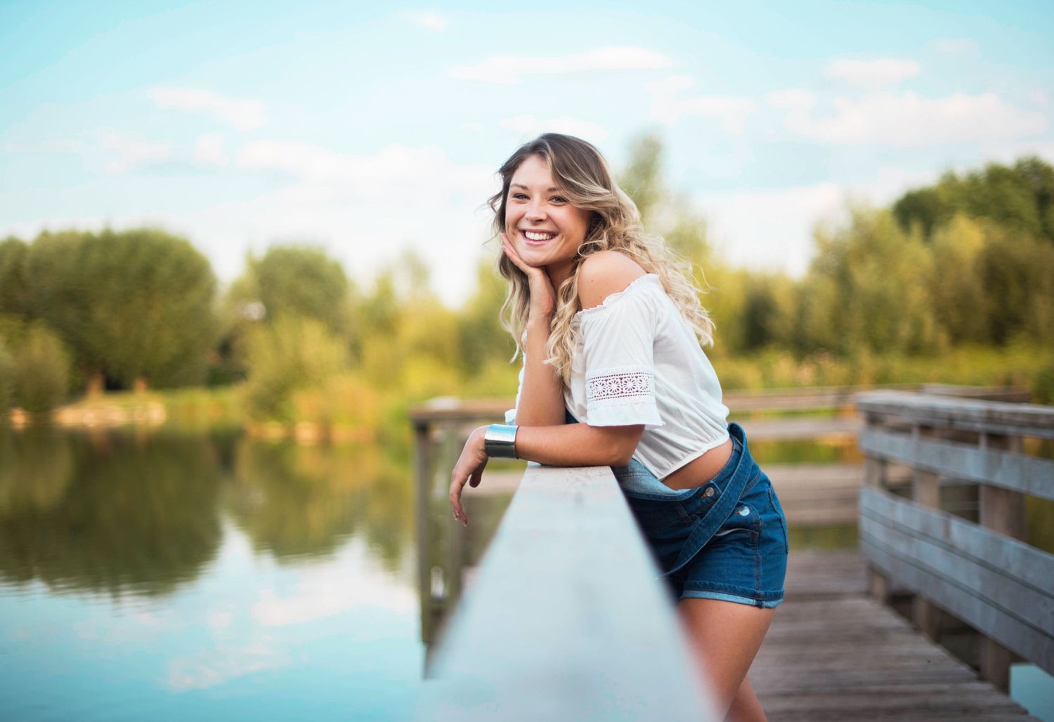 Casual summer photoshoot on wooden dock overlooking peaceful lake.
