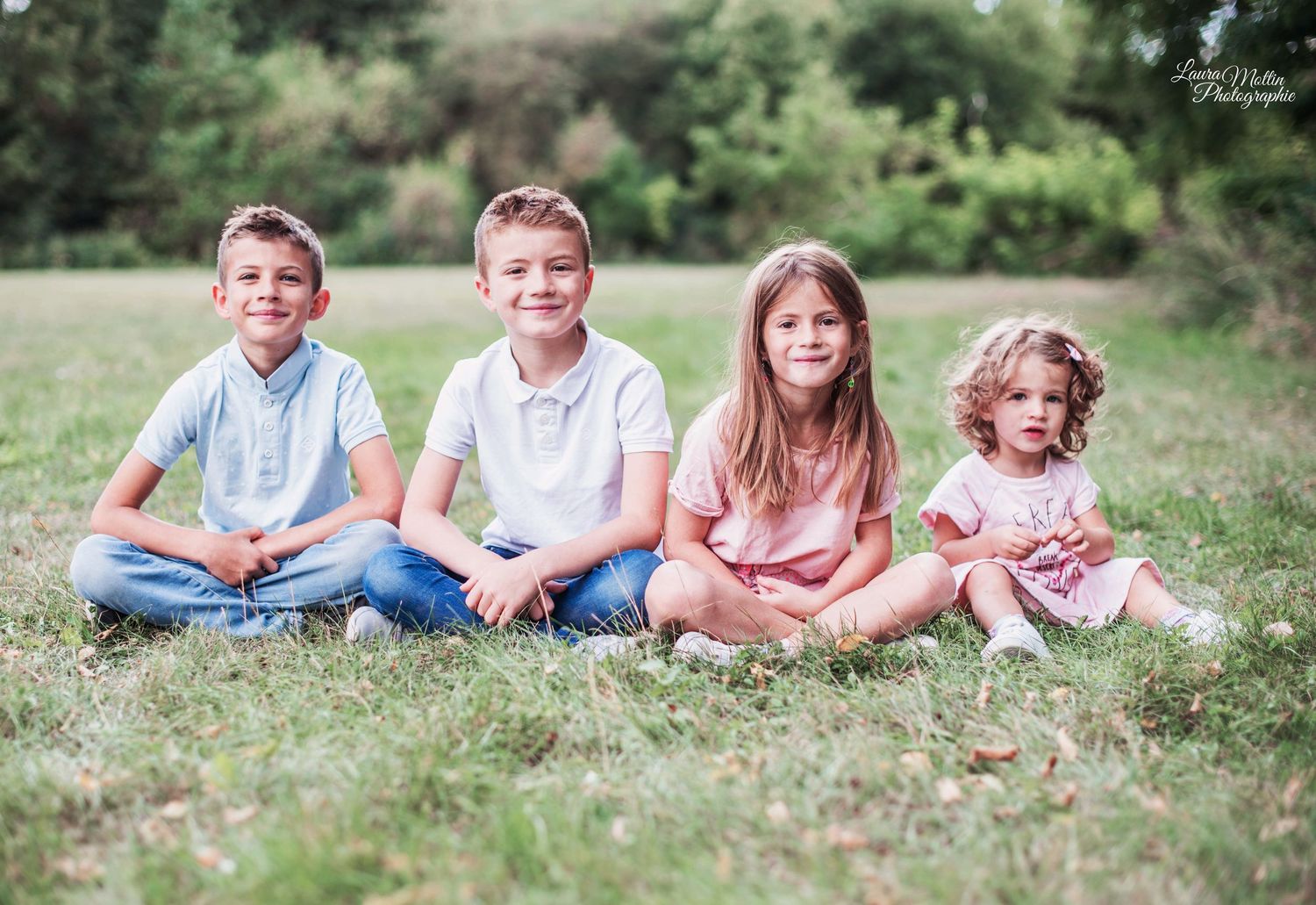 Children laying in grass during an outdoor photo session in natural lighting.