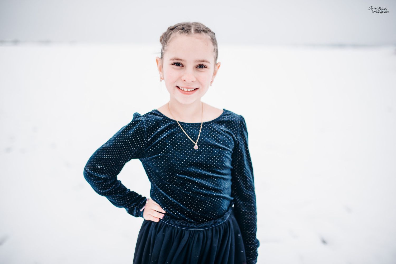 Winter portrait session featuring someone in a navy blue dress against a snowy backdrop.