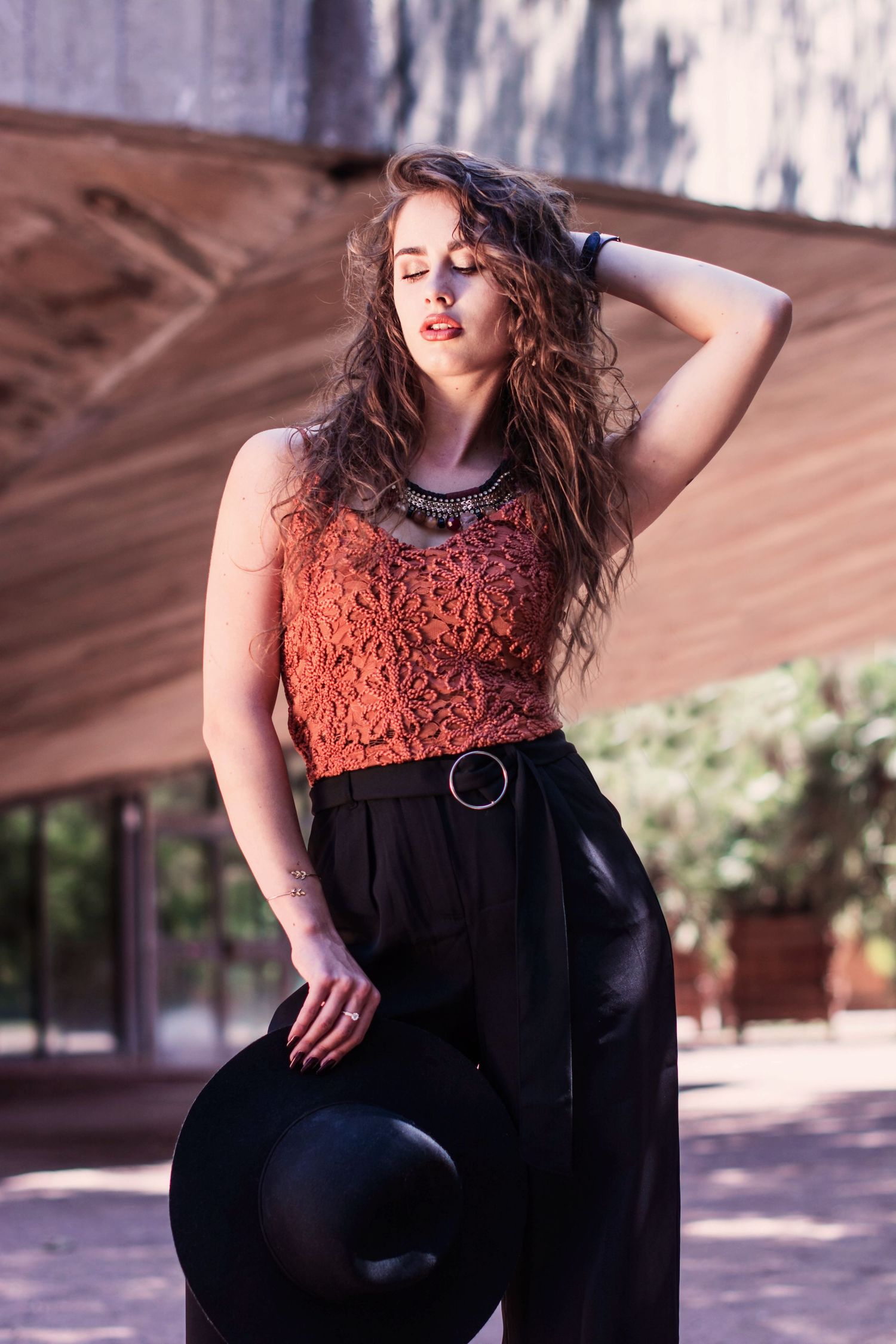 Fashion portrait featuring a rust-colored lace top paired with black clothing in an outdoor setting.