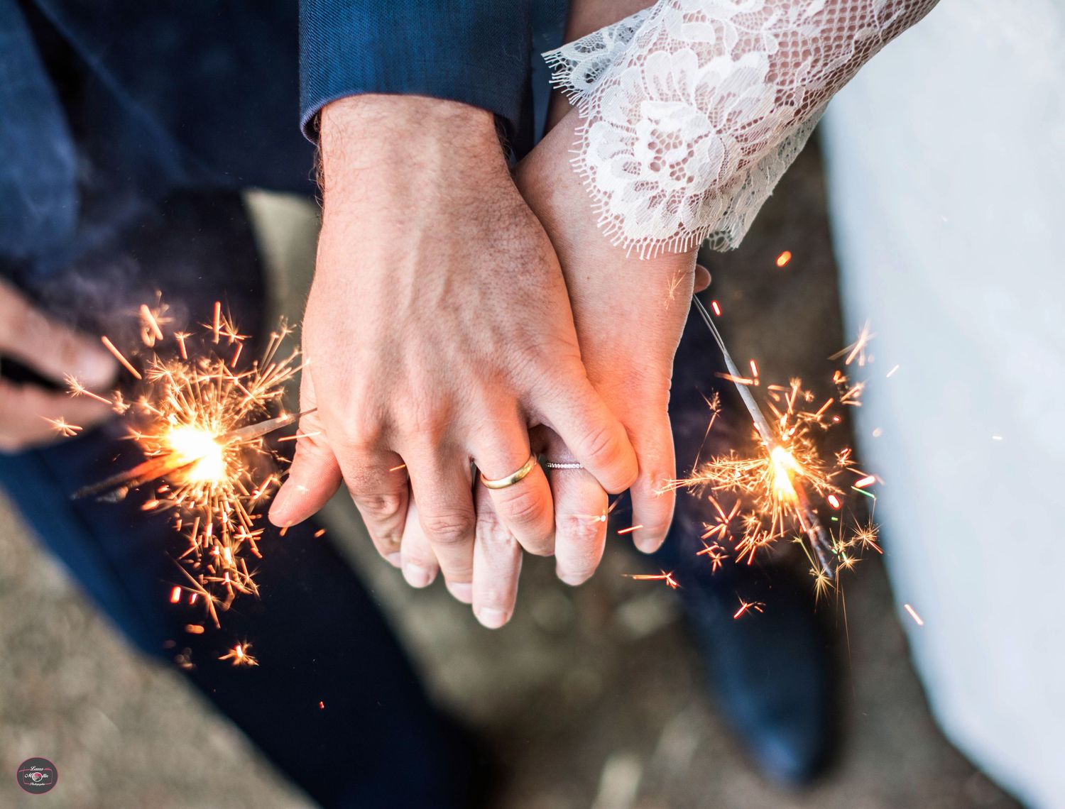 Close-up of hands holding sparklers during wedding celebrations.