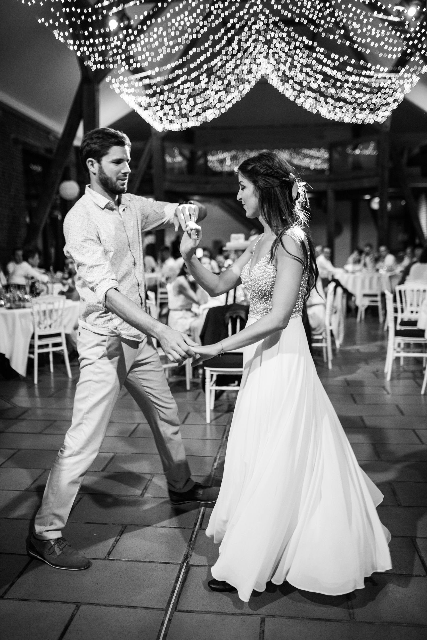 Couple dances under twinkling string lights at their wedding reception.