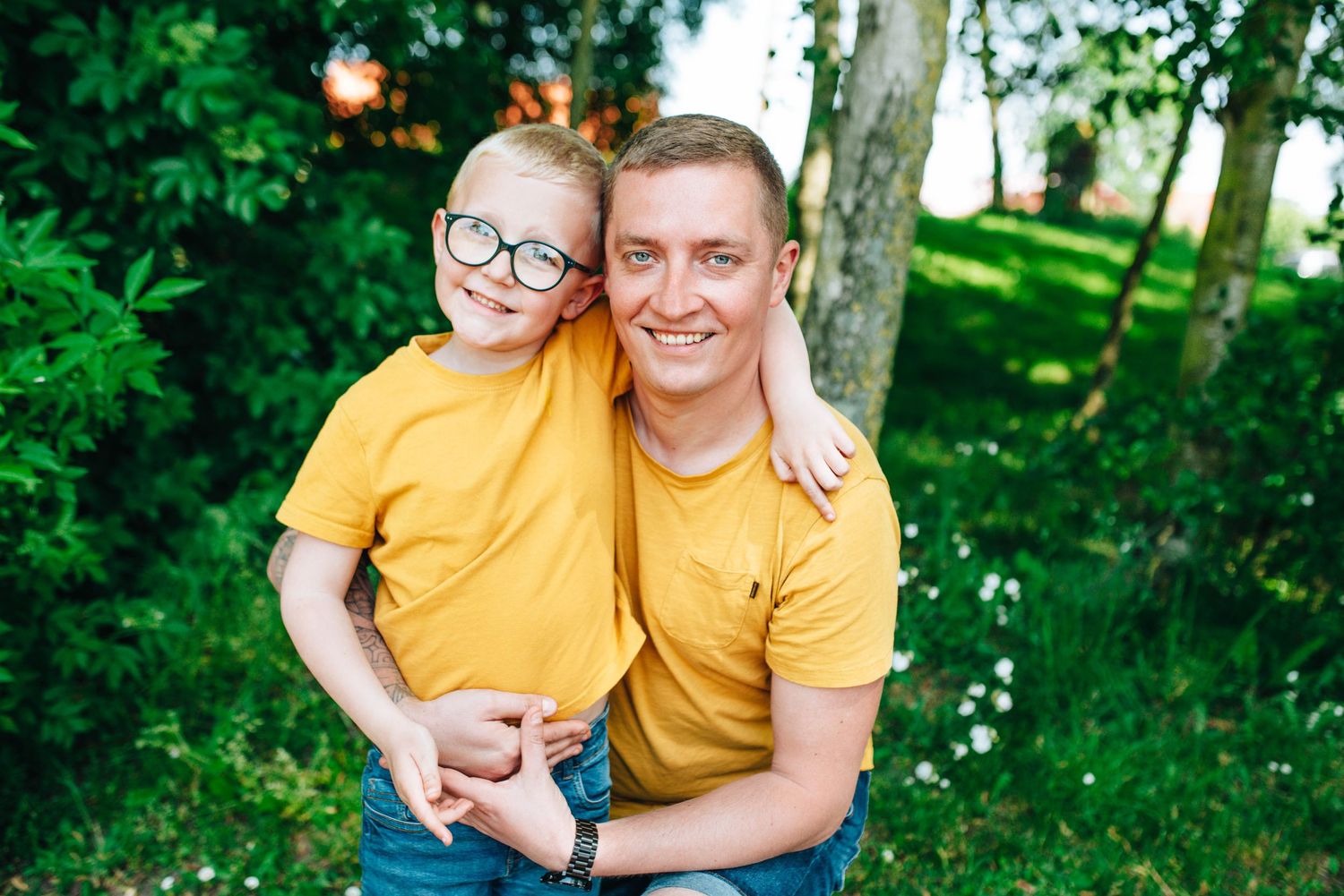 Family wearing matching yellow shirts enjoying time together in a lush green park.
