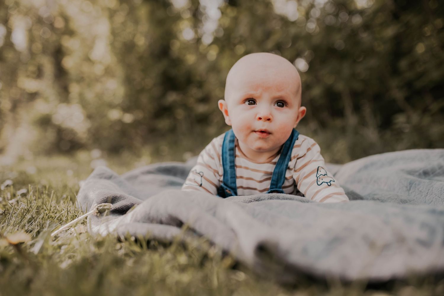 Series of artistic outdoor baby portraits taken on textured stone surface.