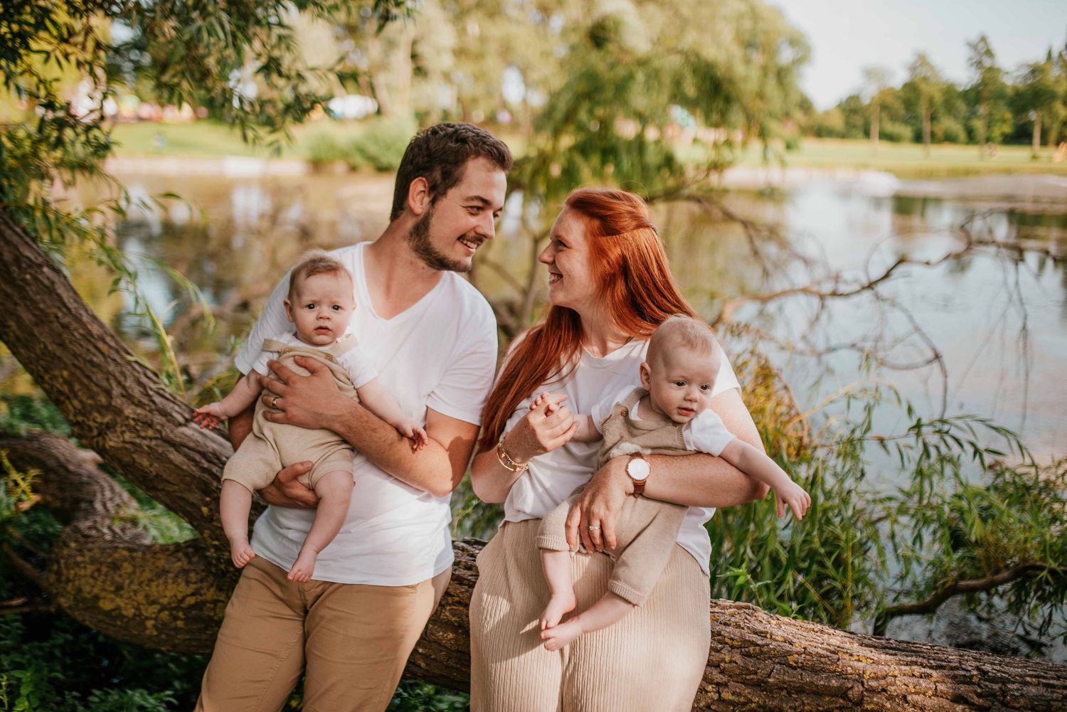 Family enjoying tender moments by lakeside during sunset photoshoot.