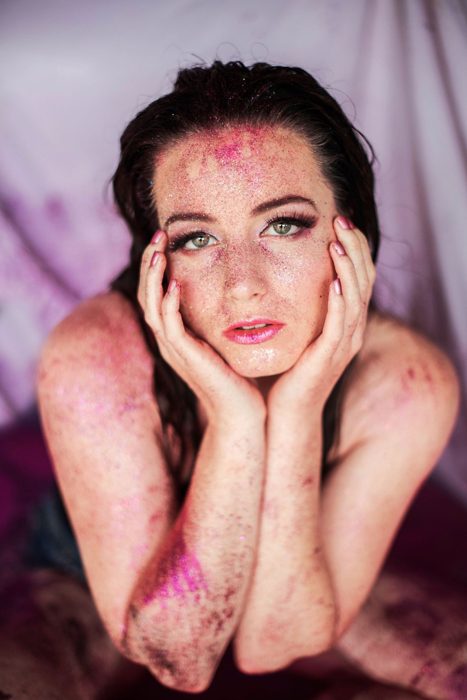 Creative portrait series with hands framing face against purple backdrop.