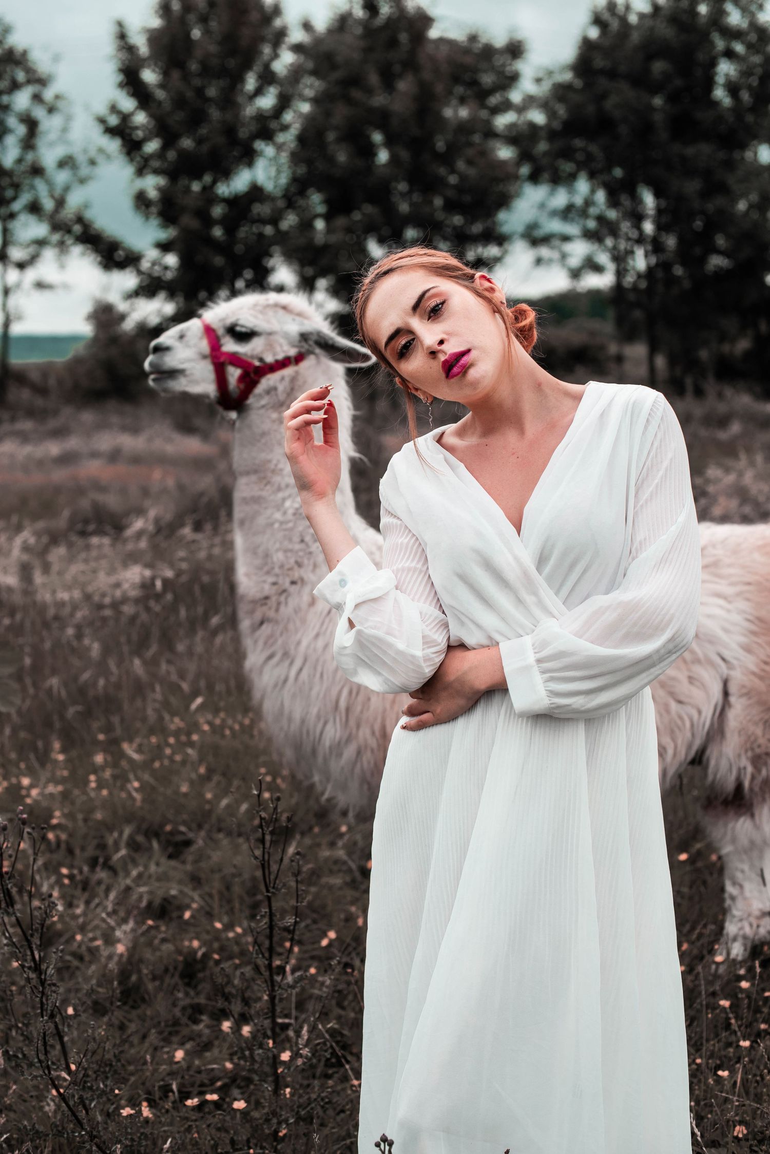 Artistic fashion portraits in flowing white dress against rustic outdoor backdrop.