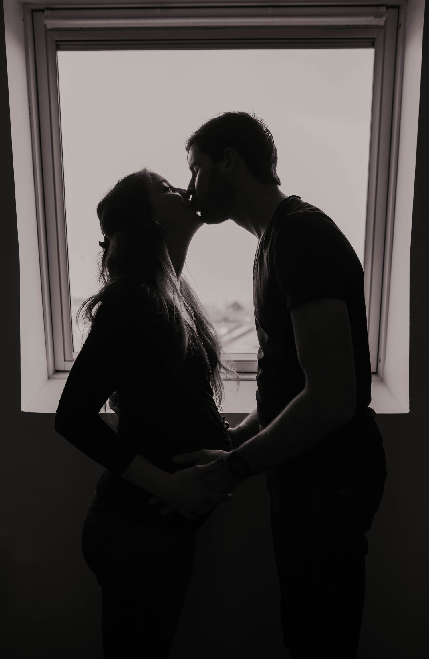 Silhouetted figures embrace in a romantic sequence against a window backdrop.
