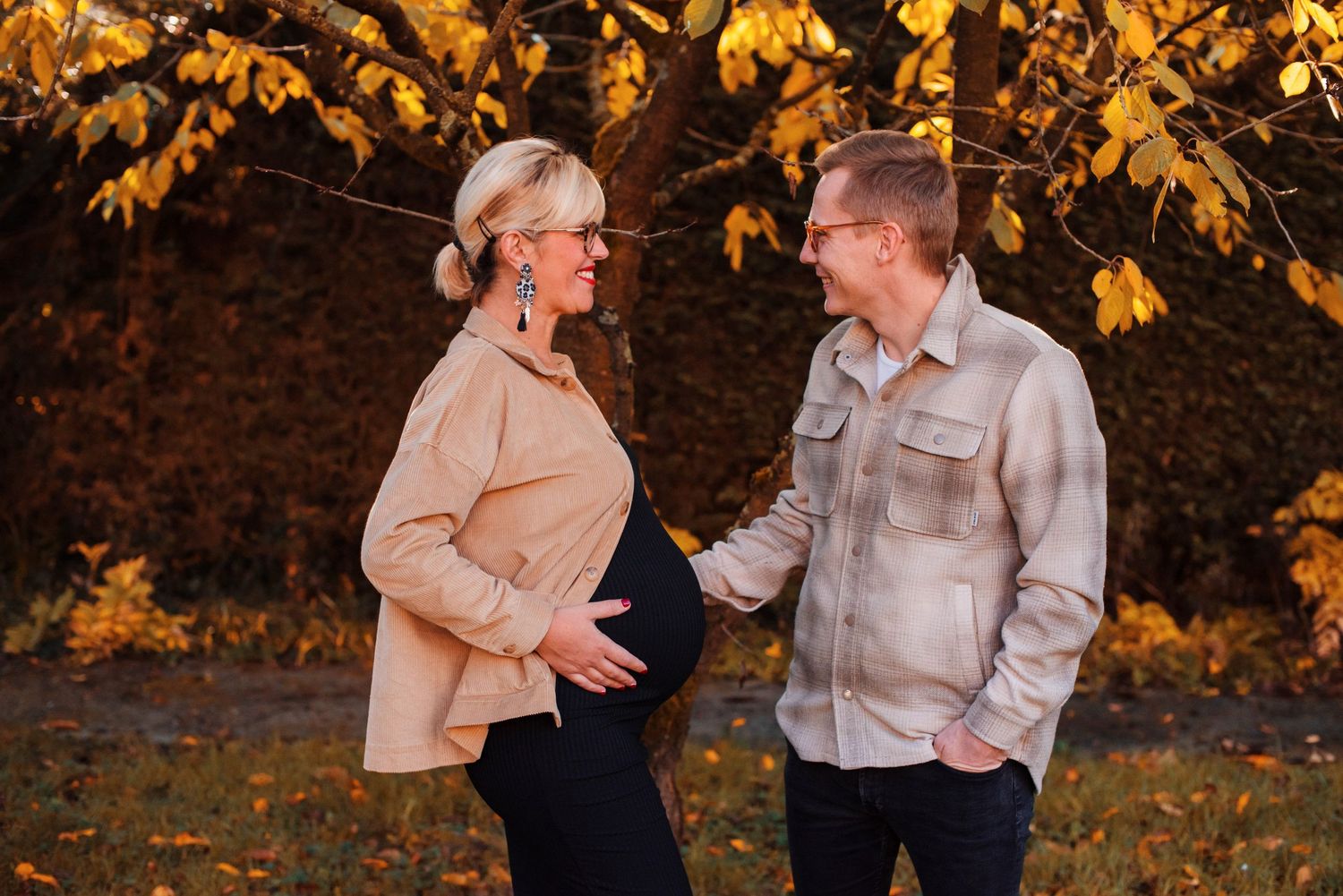 Couple sharing tender moment outdoors with autumn leaves in background.
