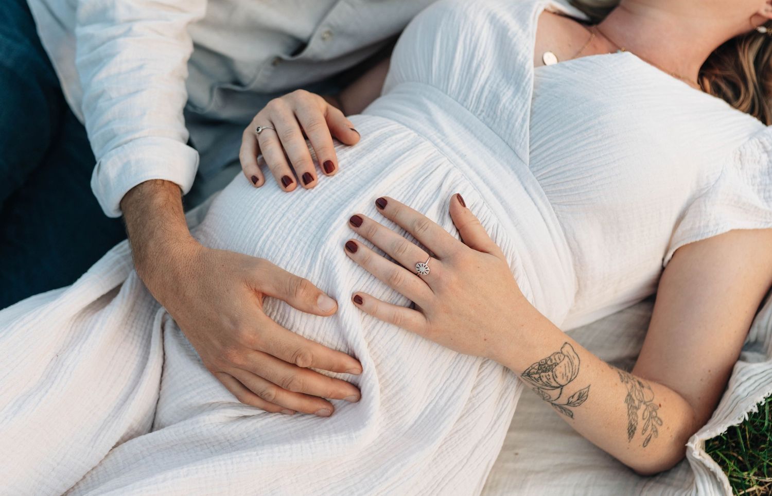 Intimate close-up shots of hands resting on a pregnant belly in white fabric.