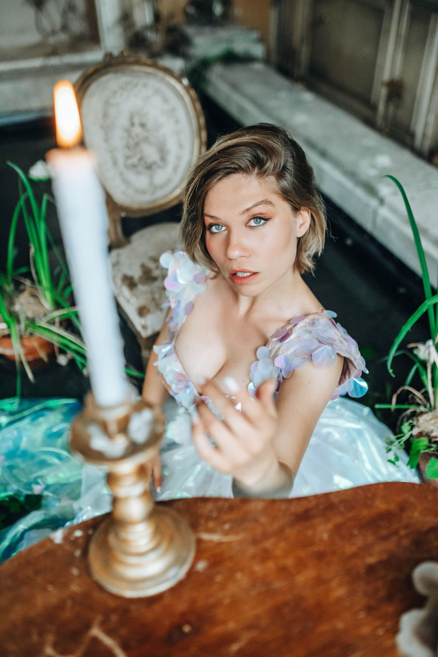 Artistic portrait with white candles and vintage wooden table in moody lighting.