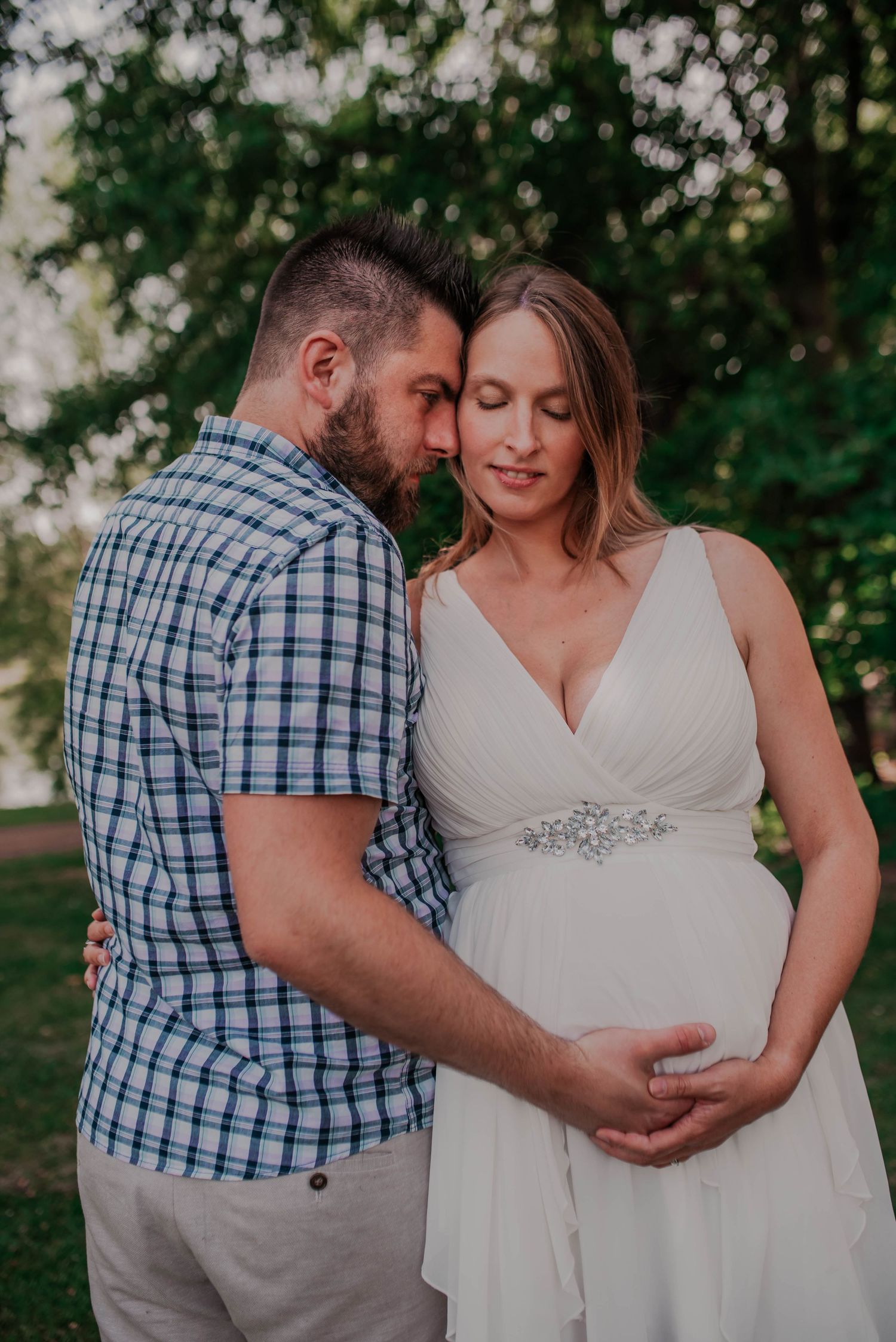 Couple shares tender moments outdoors in a white dress and plaid shirt.