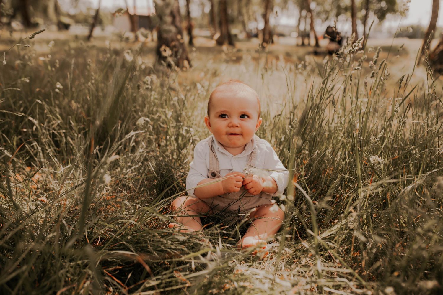 A joyful family photoshoot in a natural outdoor setting with tall grass.