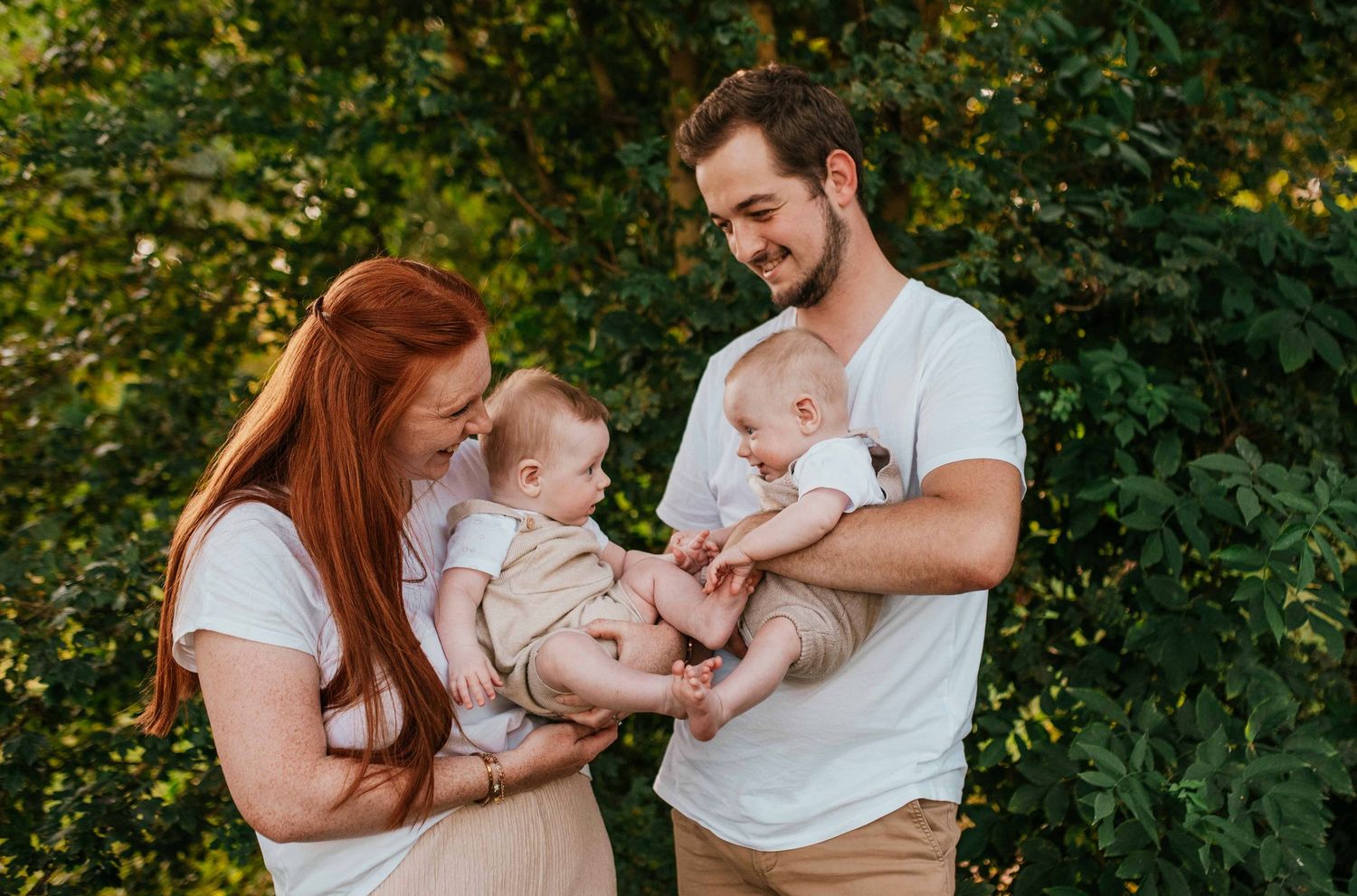Family plays together outdoors with their baby in a natural setting.