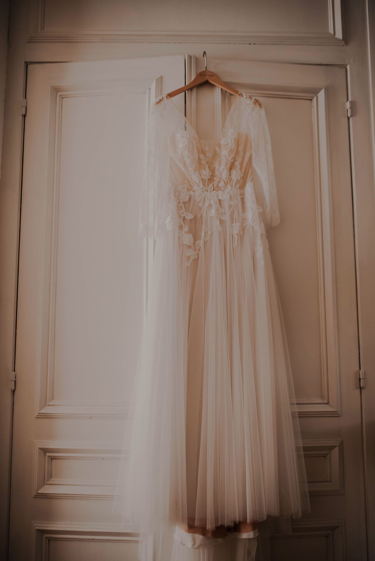 Elegant white wedding dresses hanging on display against a neutral wall.