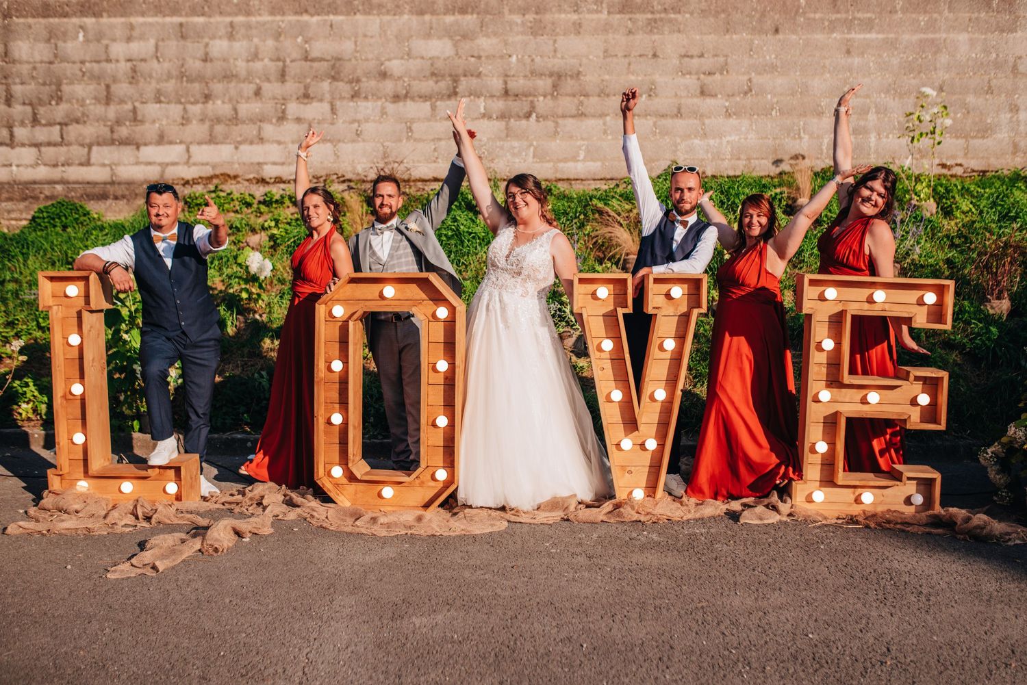 Outdoor wedding reception setup with rustic LOVE letters and party decorations at sunset.