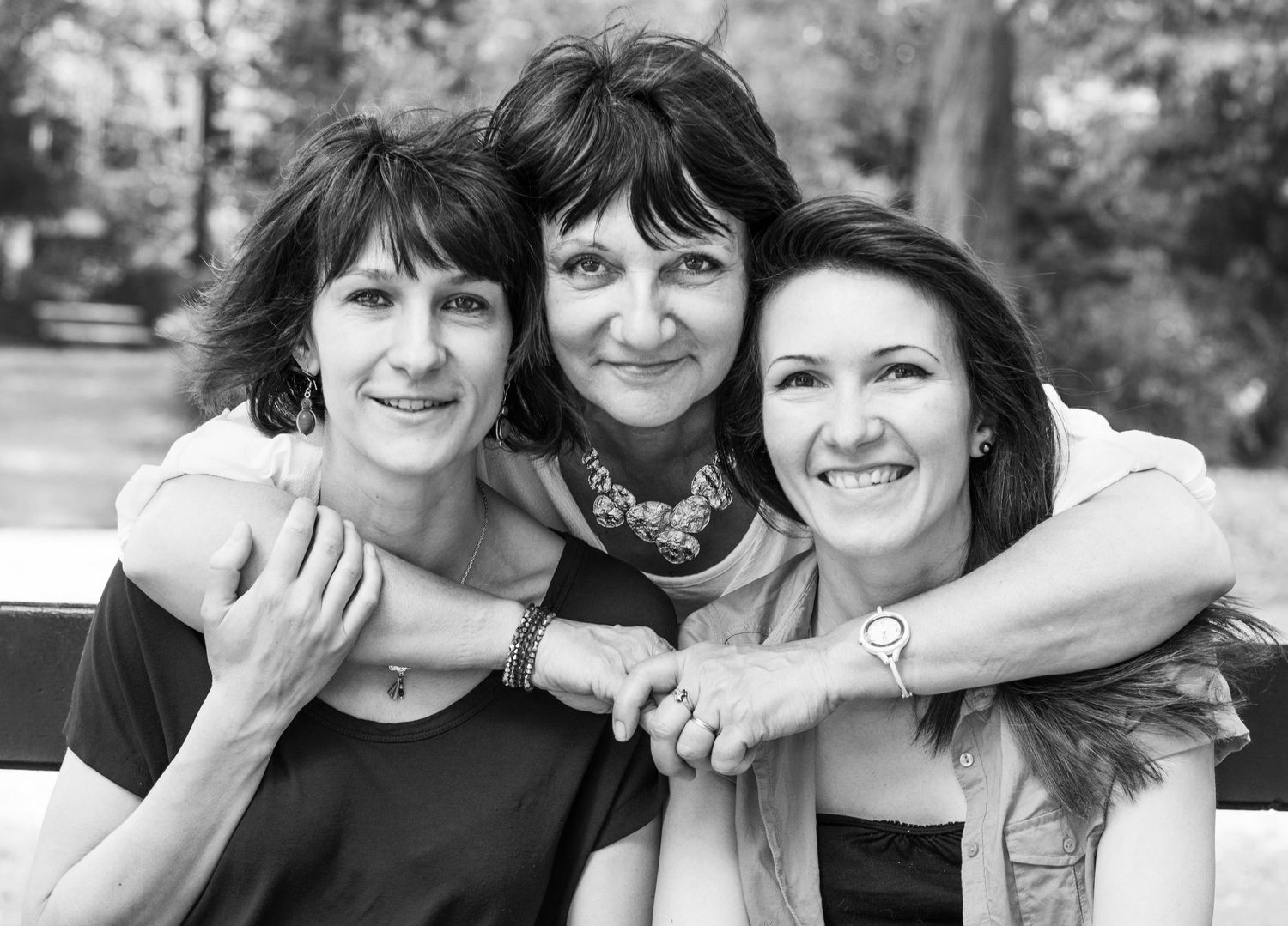 A black and white close-up portrait of three women embracing and smiling.