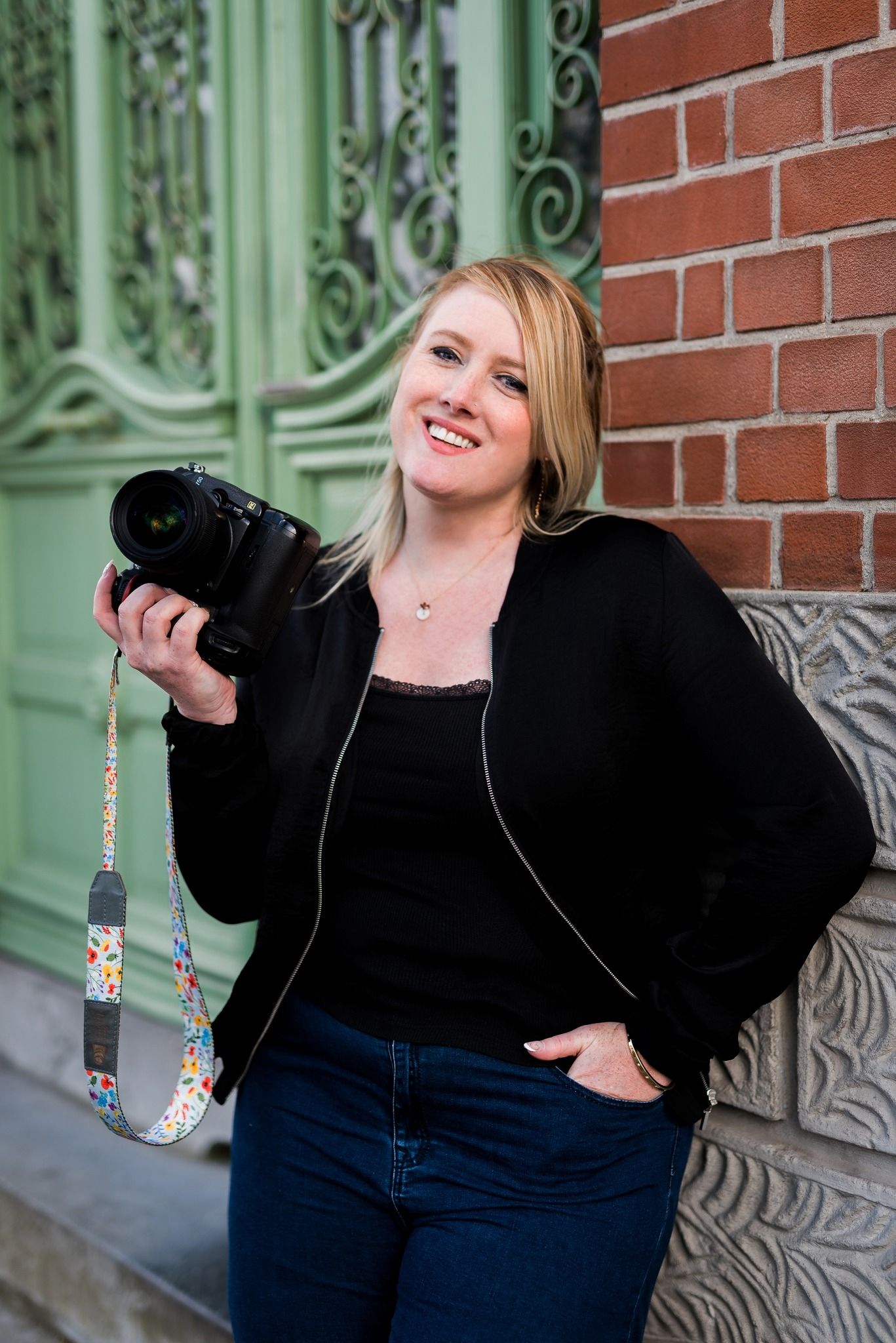 Photography session against brick wall with ornate green architectural details.