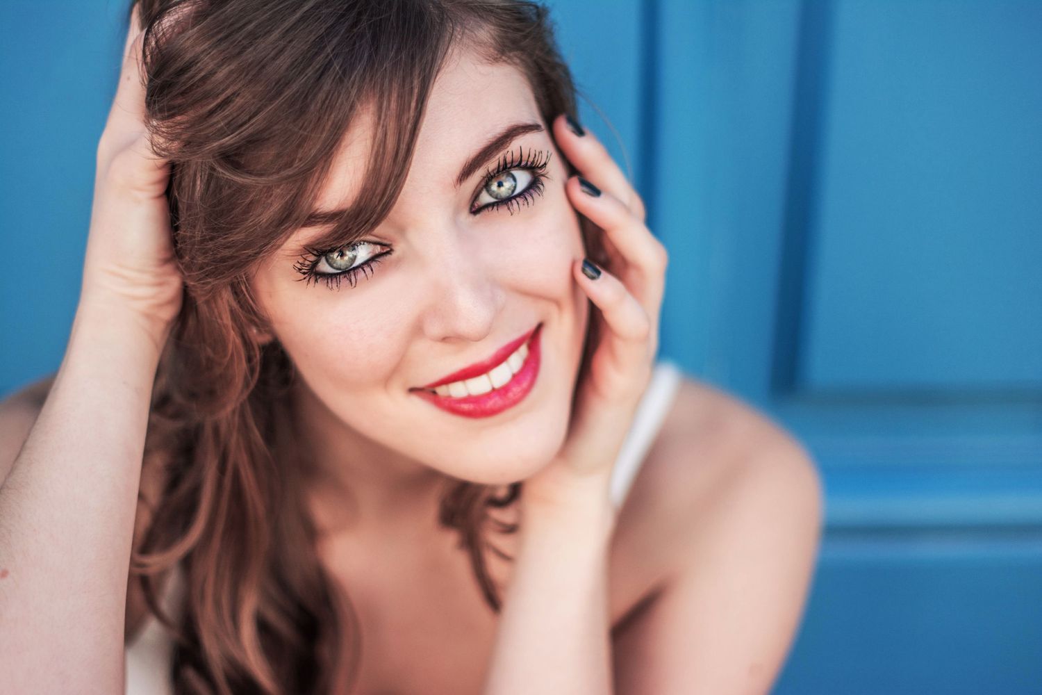 Close-up portrait with bright blue wall background.