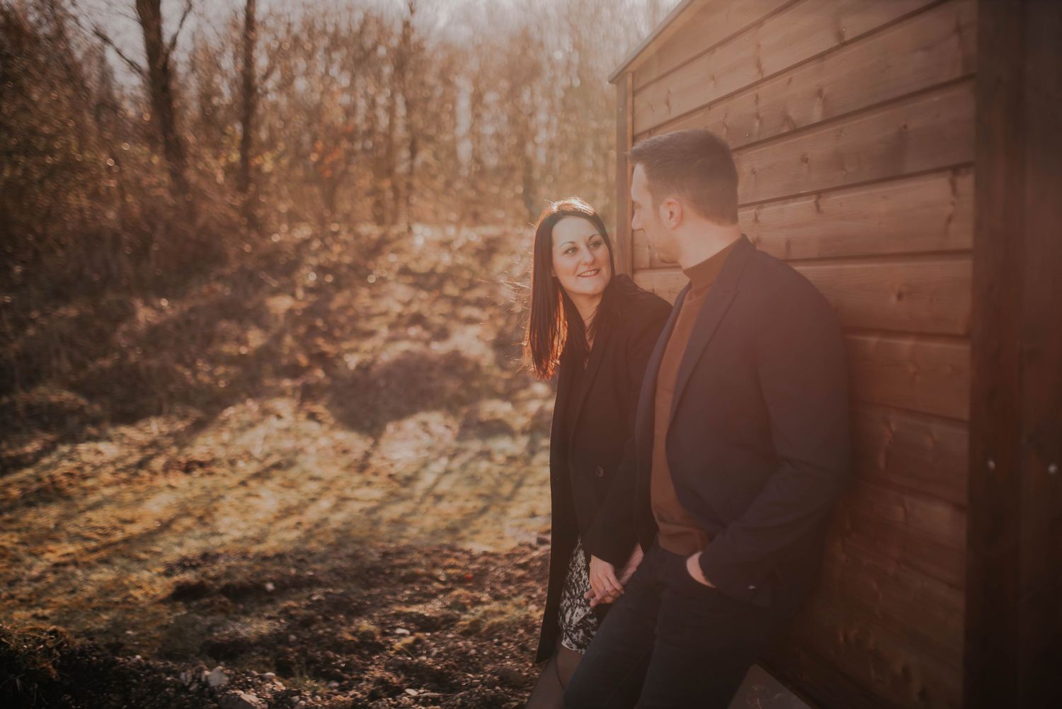 A romantic sunset photoshoot against a rustic wooden cabin wall.