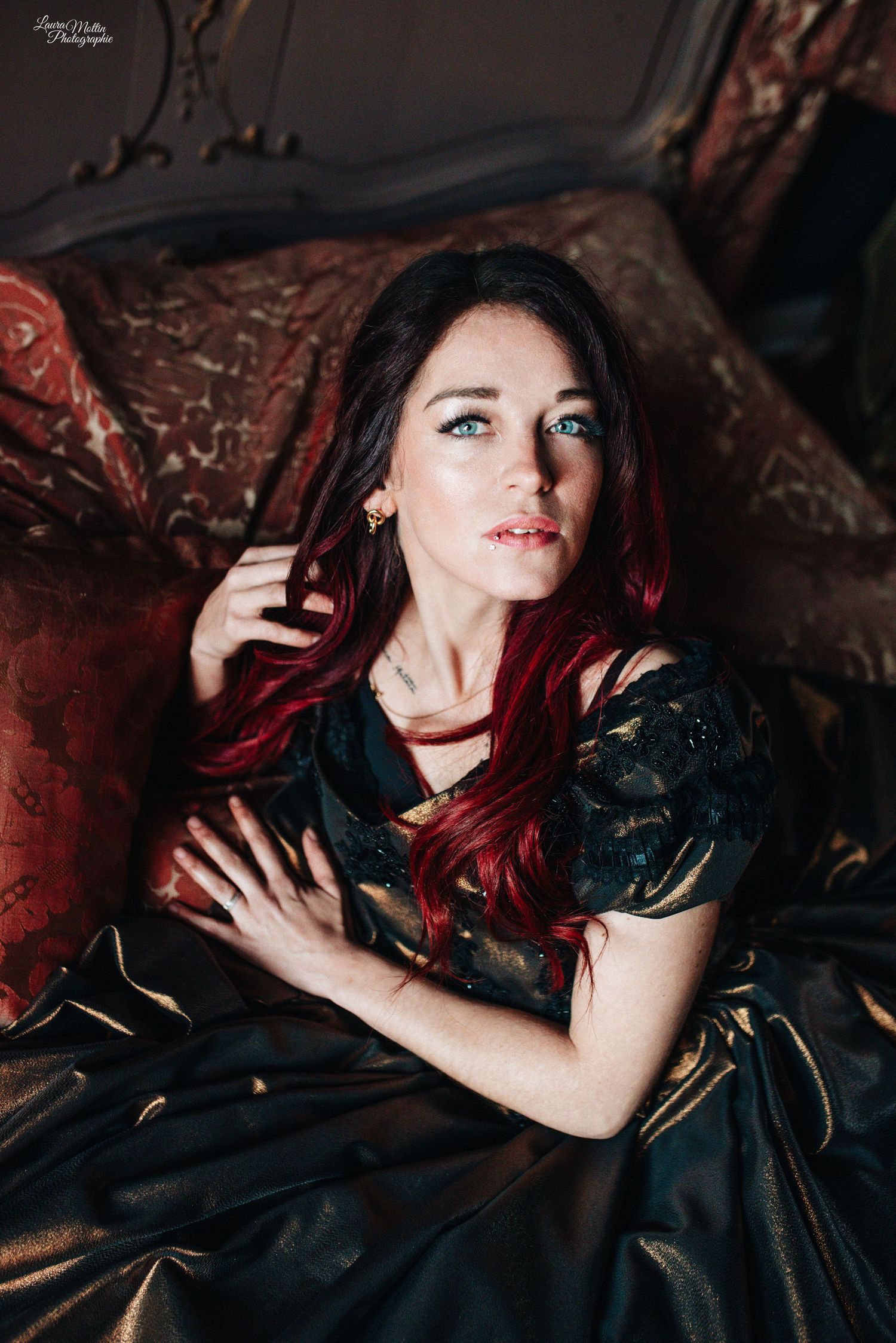 Dramatic portrait featuring dark gothic styling with red accents against black fabric in moody lighting.