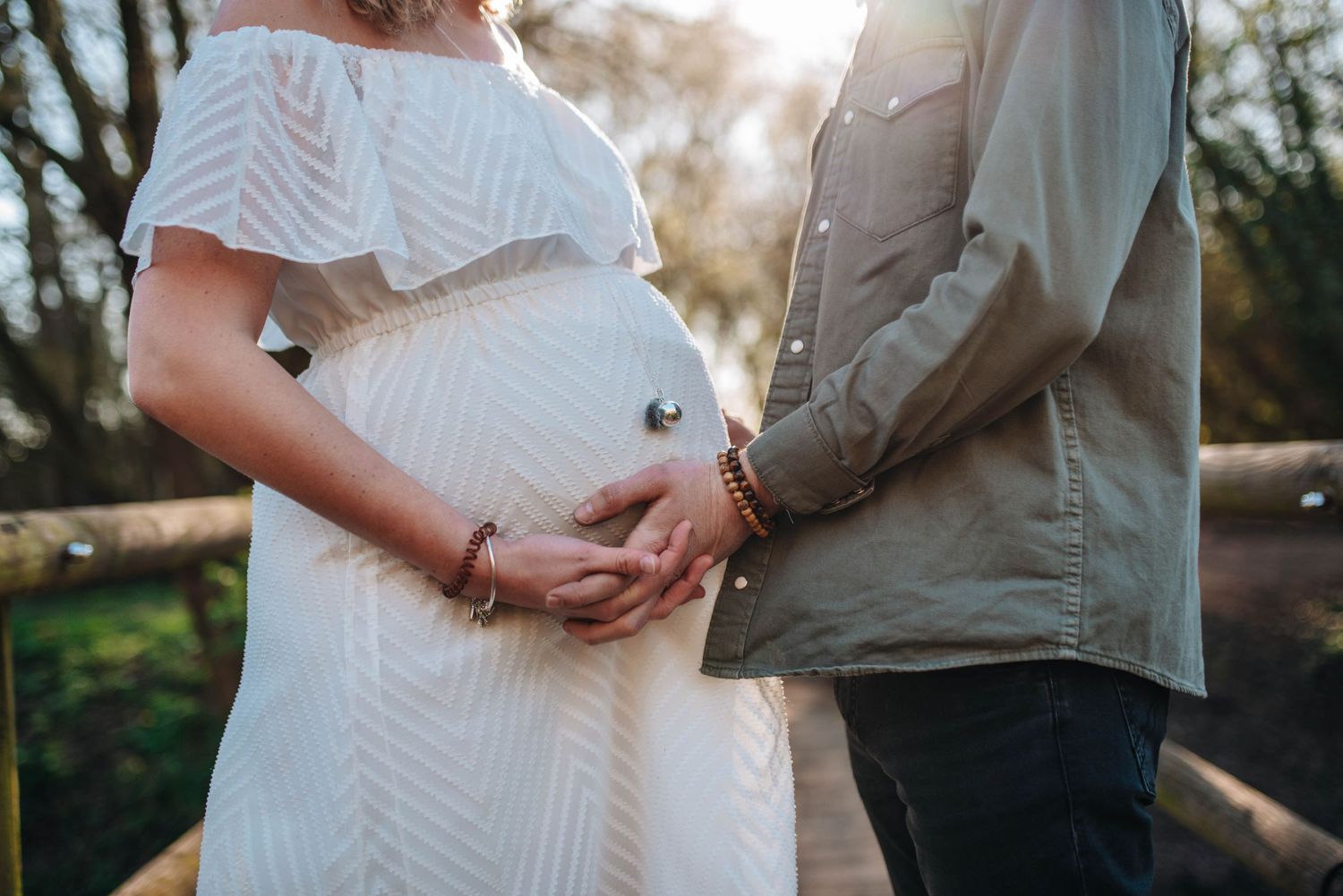 Maternity photos of couple embracing on nature trail during golden hour.