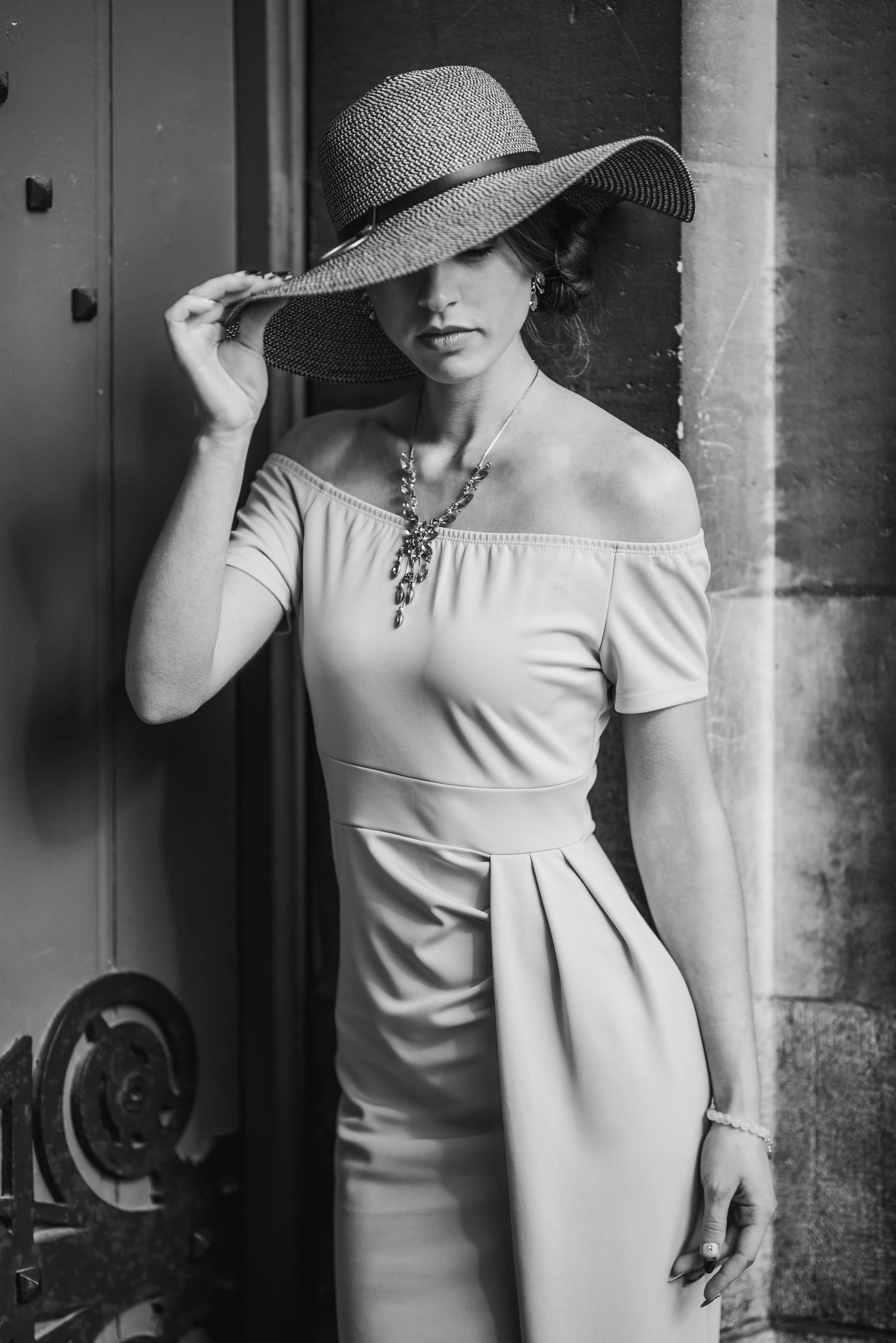 Monochrome fashion portrait with architectural elements and dramatic hat silhouette.