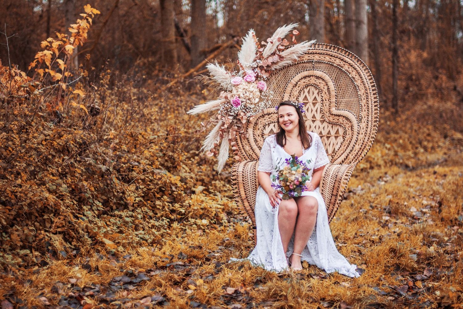 Person in white dress sitting on autumn ground with decorative circular mandala backdrop.