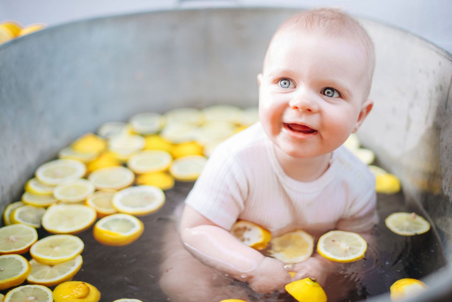 Creative baby photo featuring sliced lemons arranged in a bathtub setting.