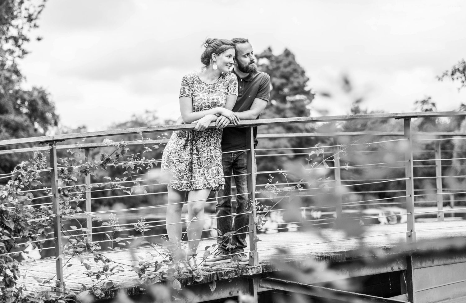 Romantic couple embracing on a wooden bridge in an outdoor setting.