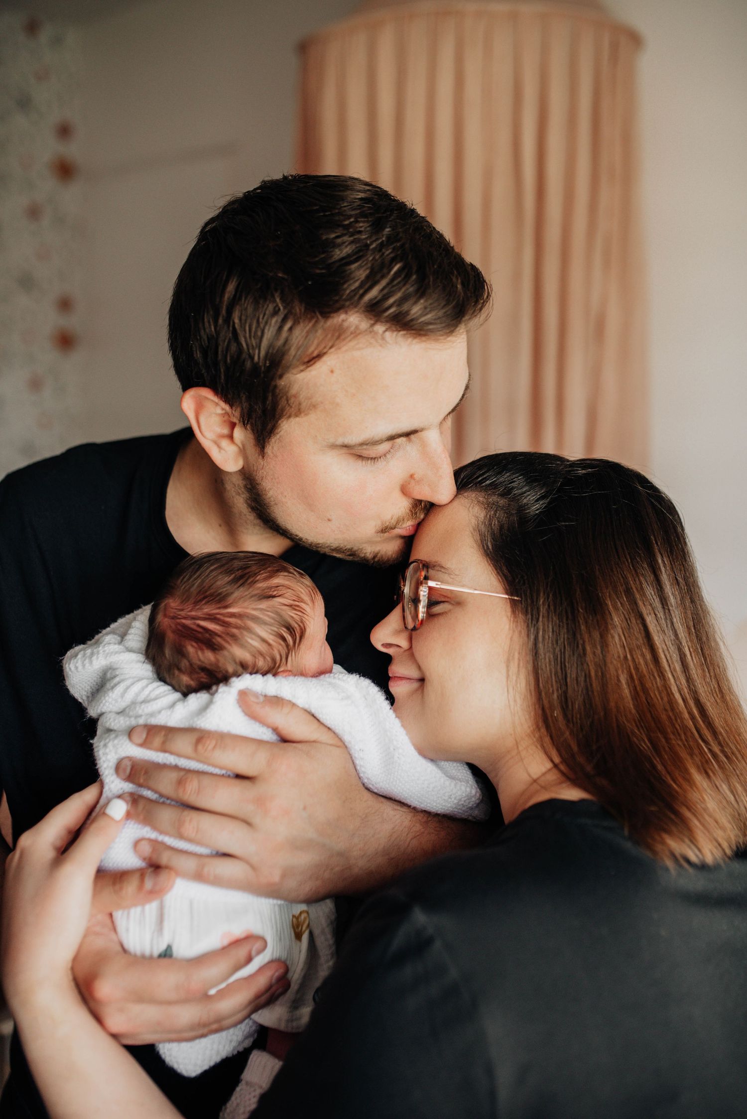 A tender family moment captured in a nursery with soft natural lighting.
