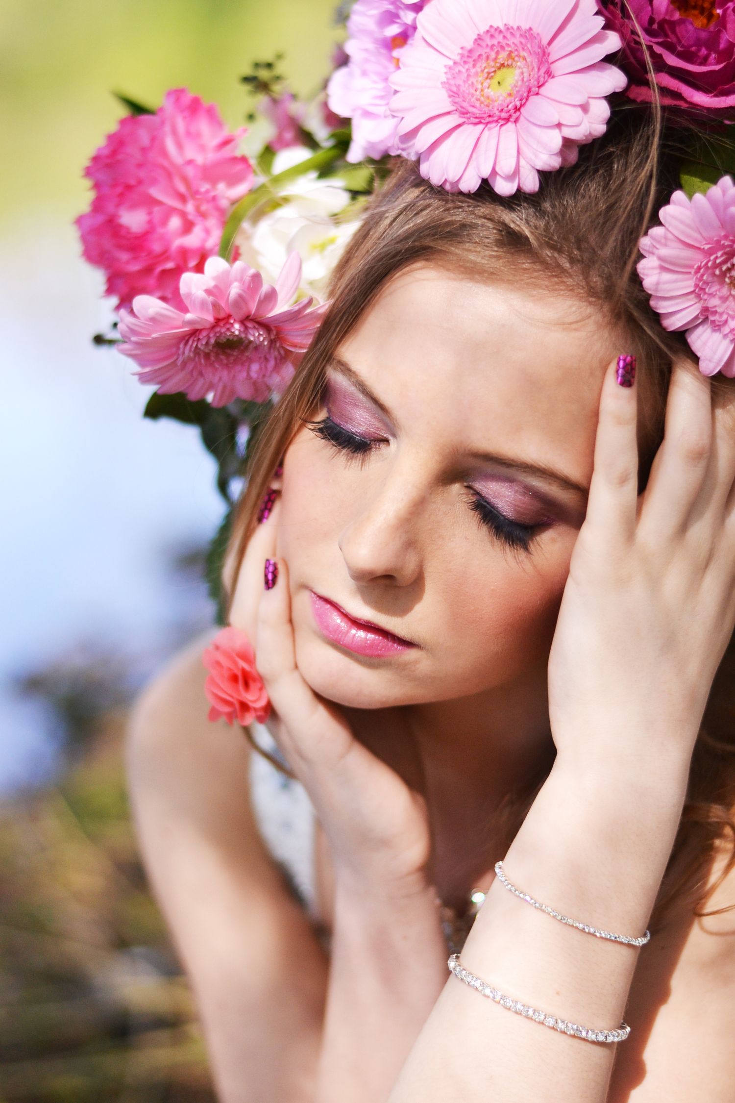 Close-up portrait with pink flower crown and delicate makeup in natural light.