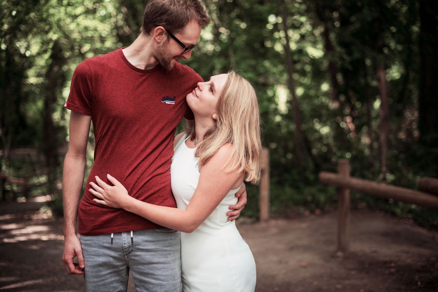 A couple shares a romantic moment on a wooded path in summer.