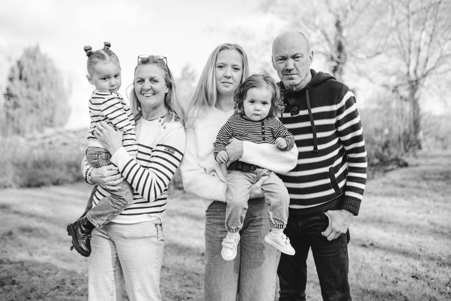 A black and white photo series showing a family playing and walking together outdoors in a natural setting.