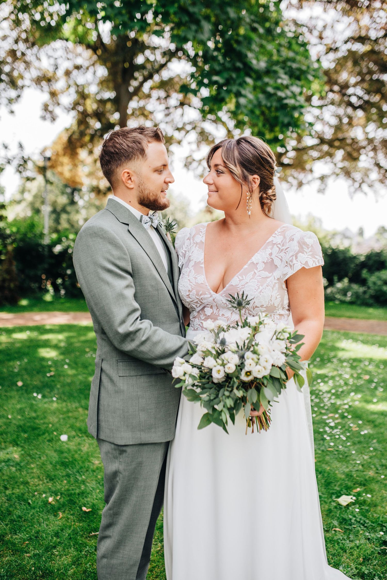 Romantic outdoor wedding portrait with lush greenery and elegant white bouquet.