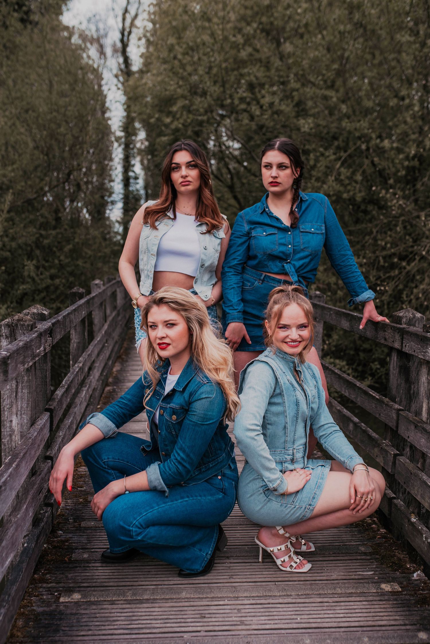 Group portrait session on wooden bridge with friends in coordinating denim outfits.
