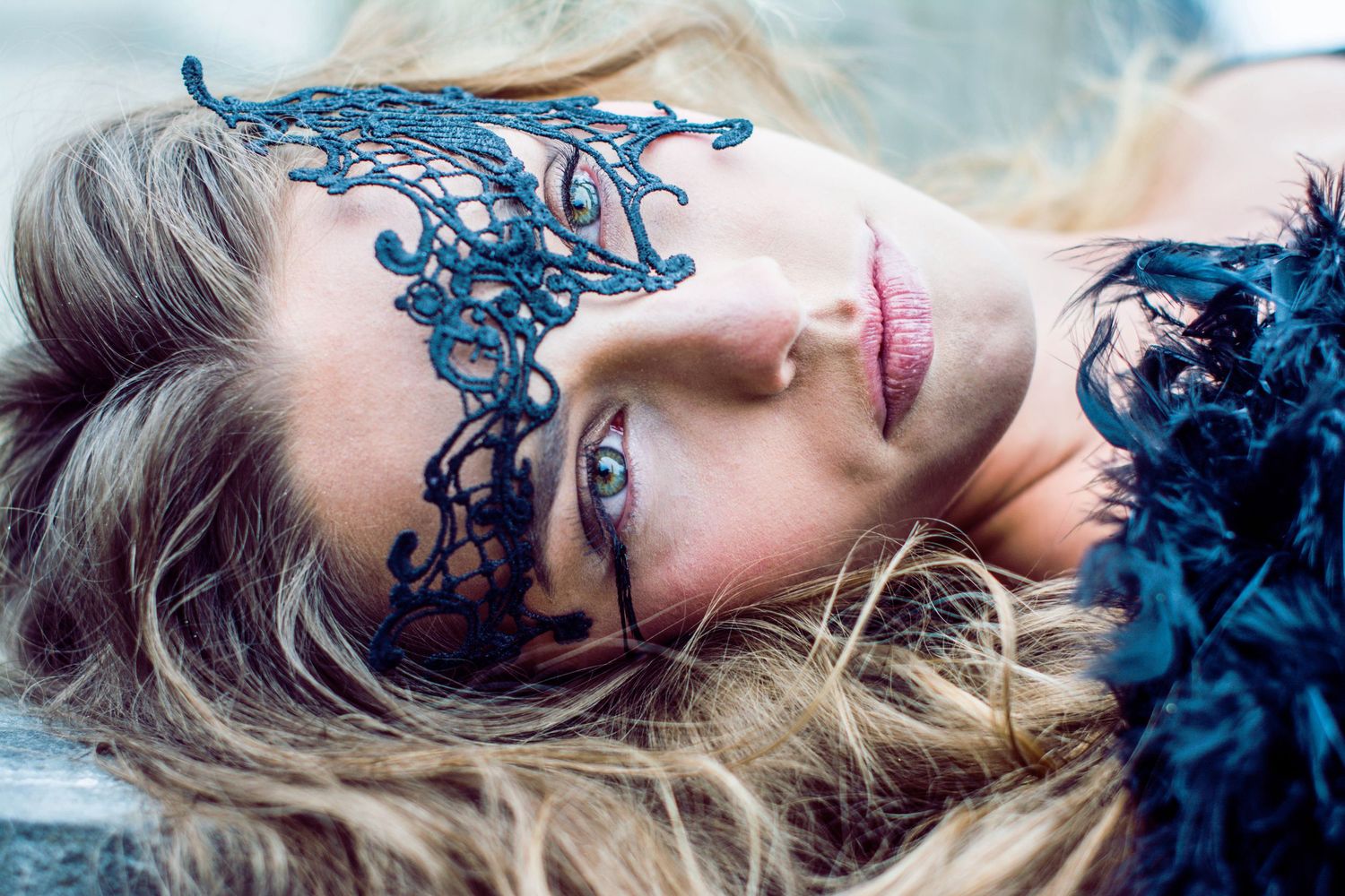 Artistic portrait with blue lace mask against light background.