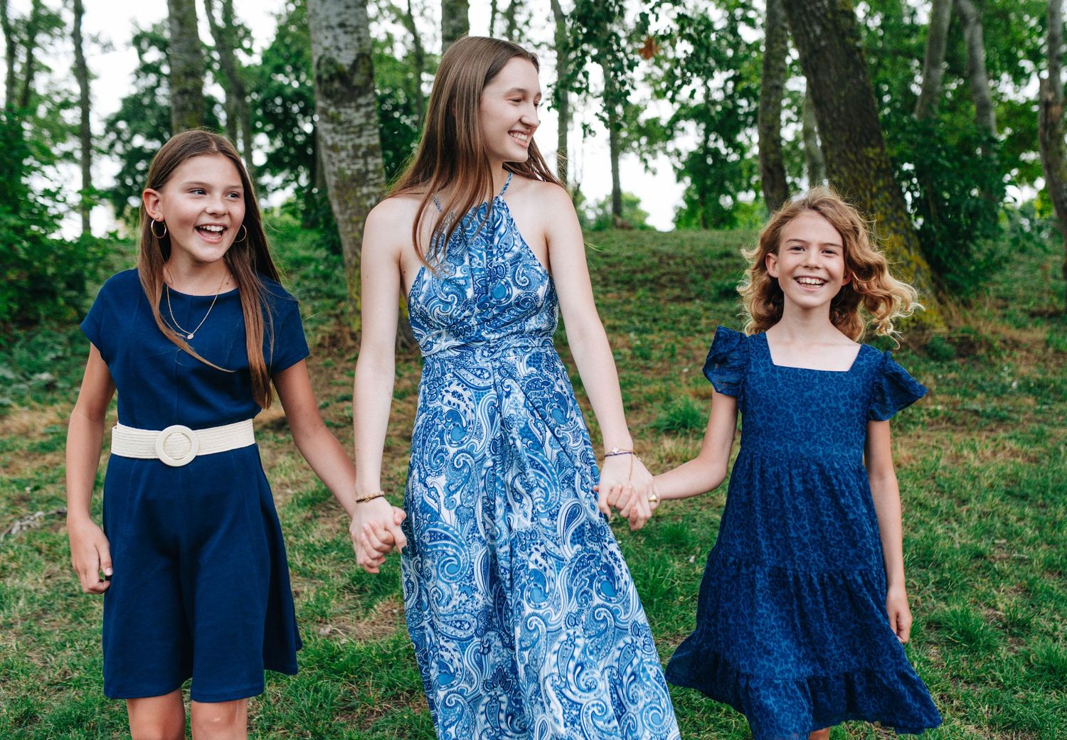 Women in coordinating blue dresses and floral prints walking together outdoors.