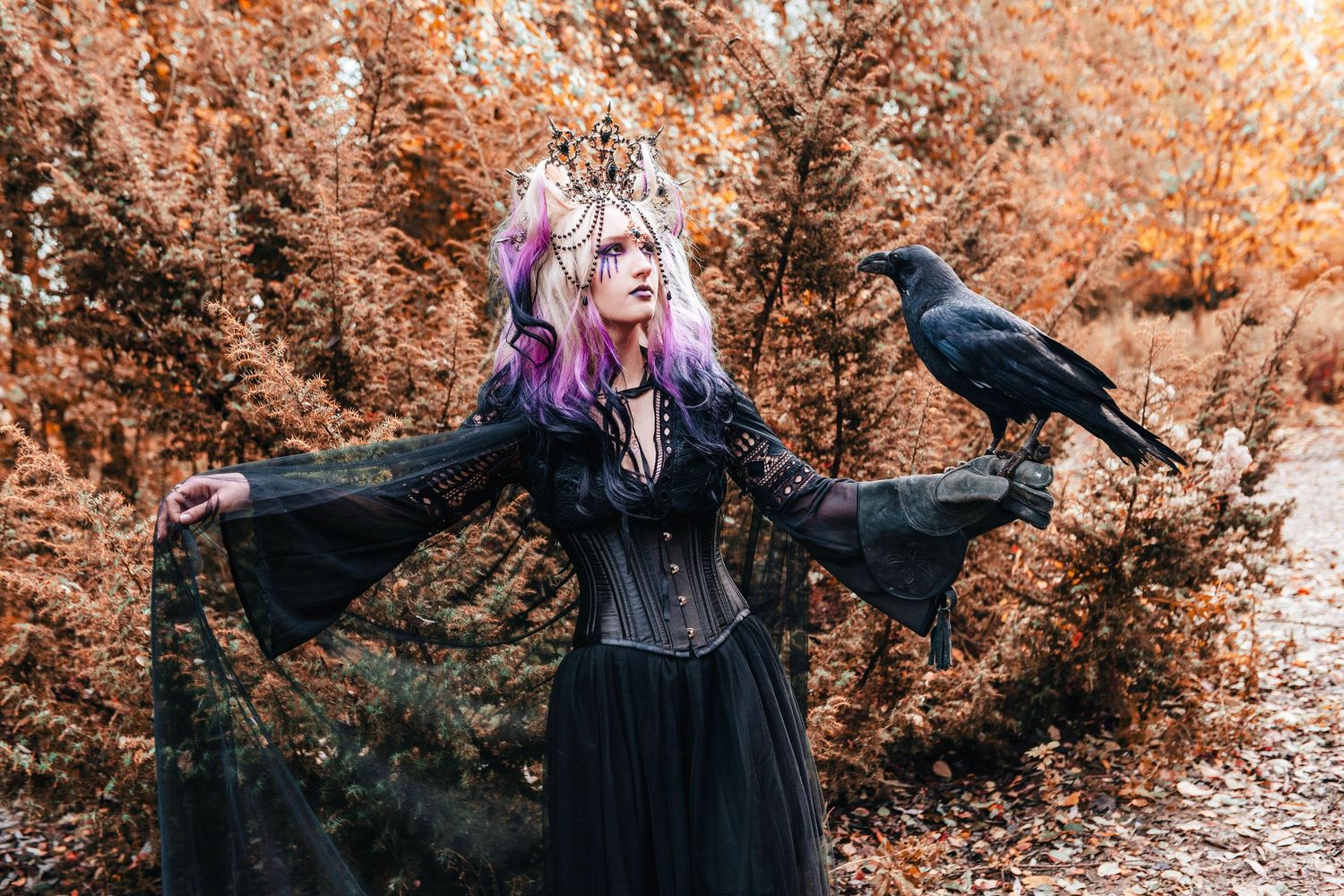 Artistic autumn photoshoot with black dress and dramatic orange-tinted foliage.