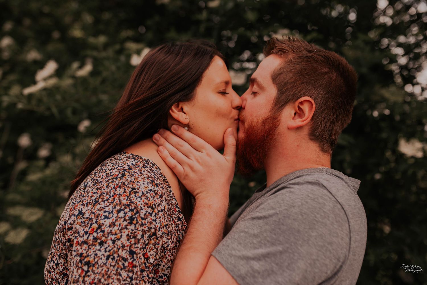 Intimate close-up of couple sharing a passionate kiss during sunset photoshoot.