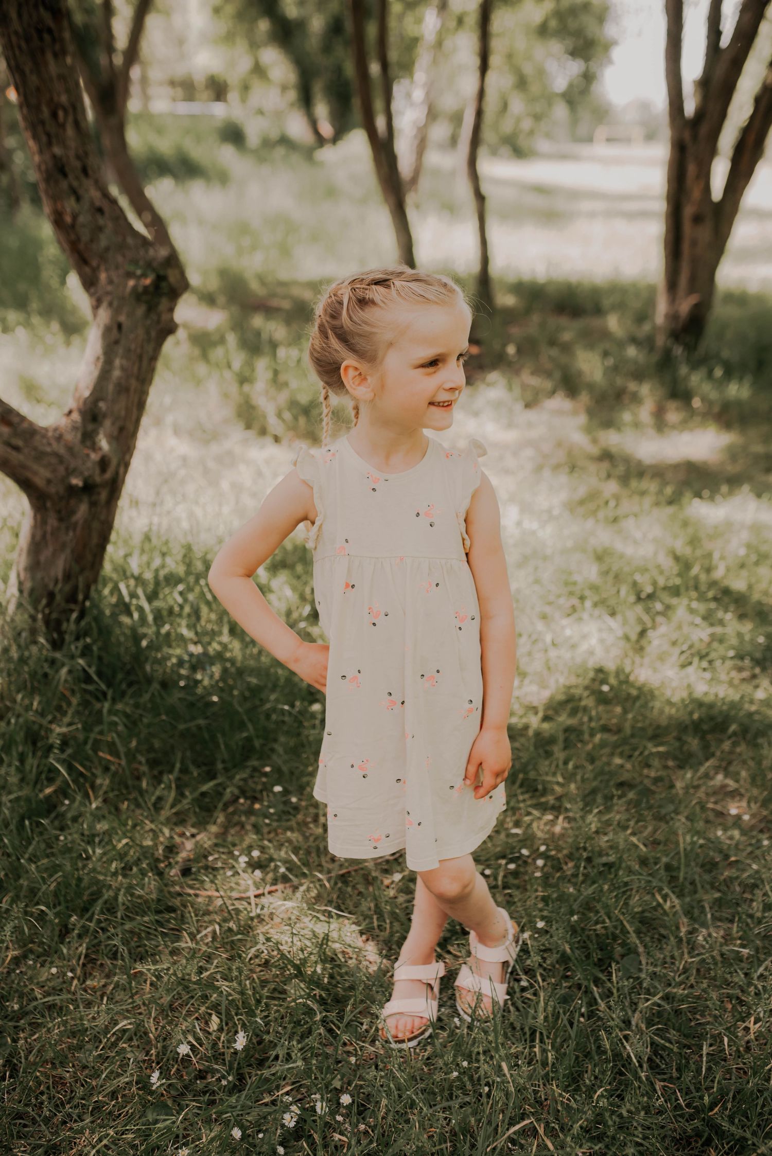 A child exploring in a wooded area wearing a light colored dress.