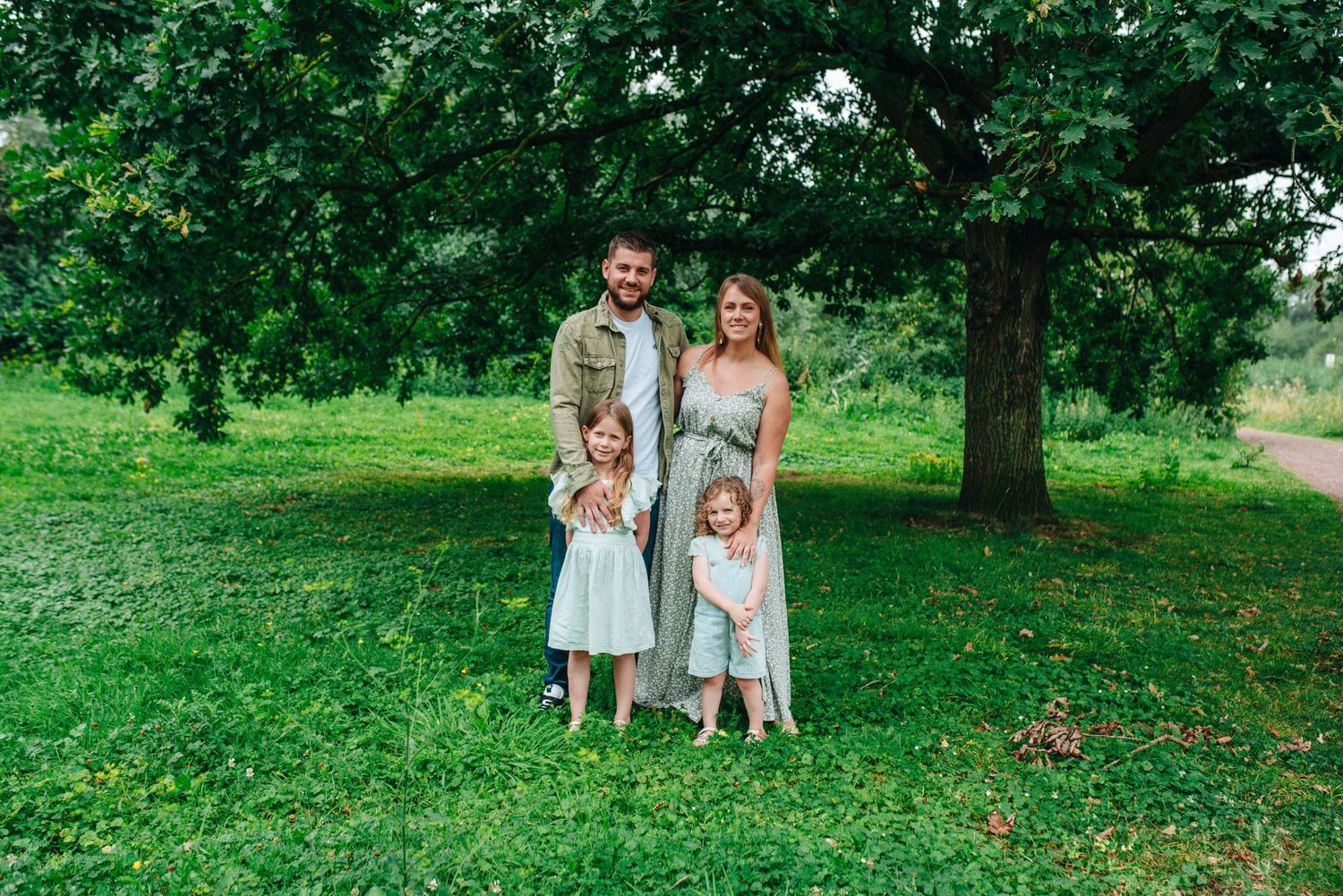 Family photoshoot in a lush green park setting during summer.