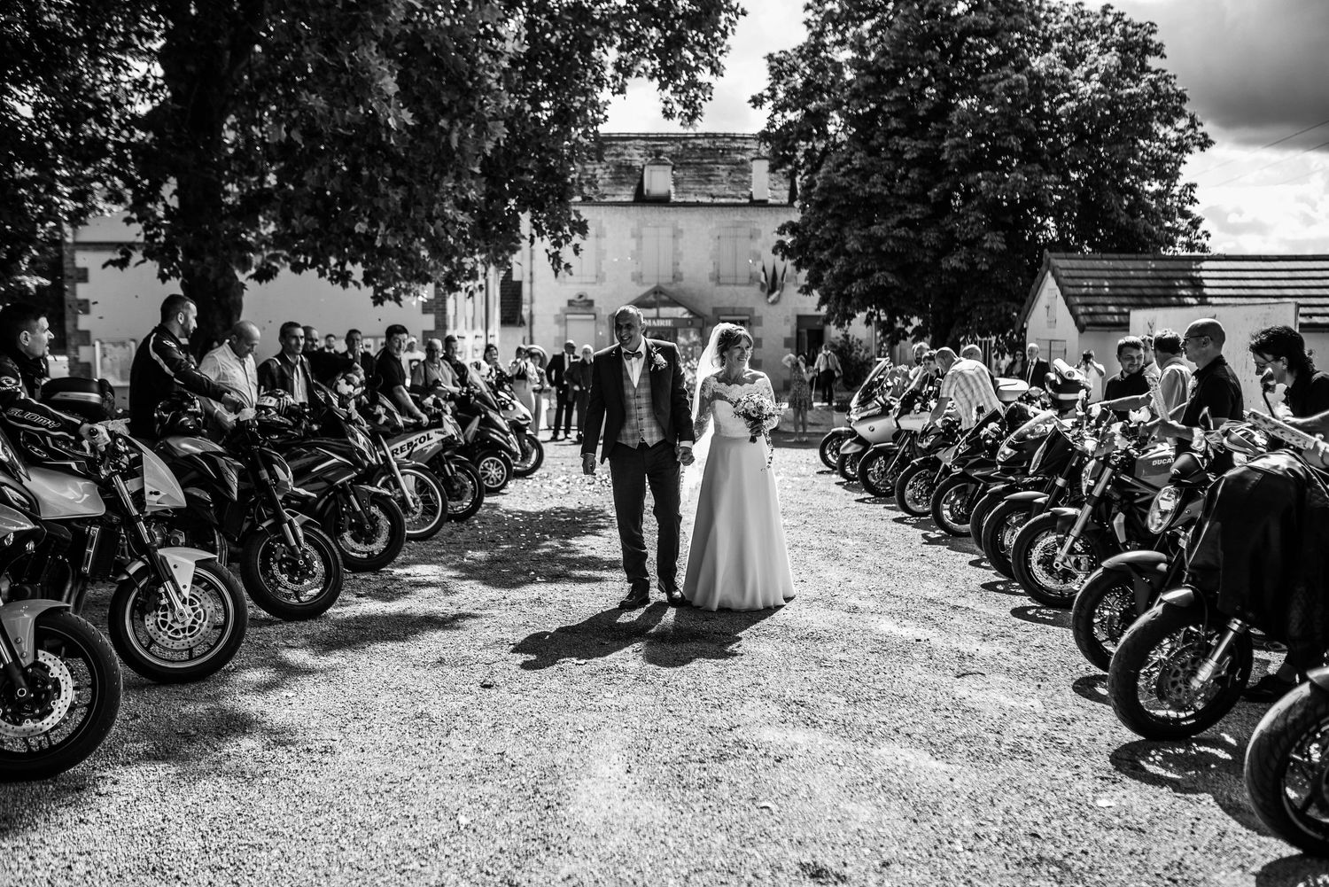 Black and white photo of motorcycles lined up at outdoor wedding venue.