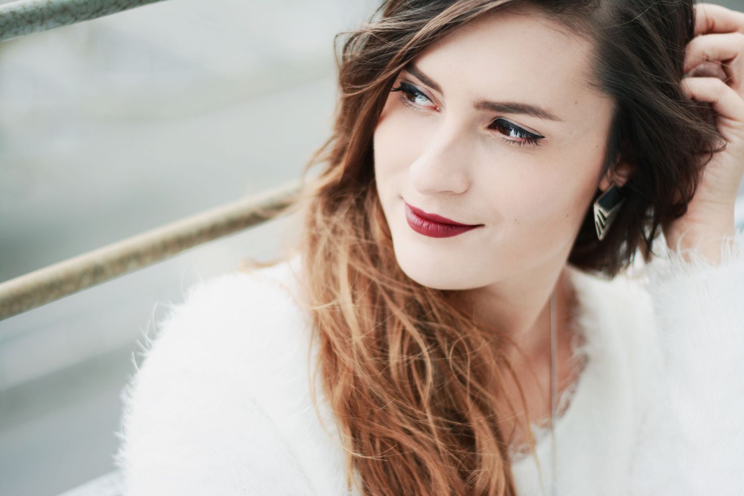 Portrait of person in white fuzzy sweater with ombre hair and red lipstick.