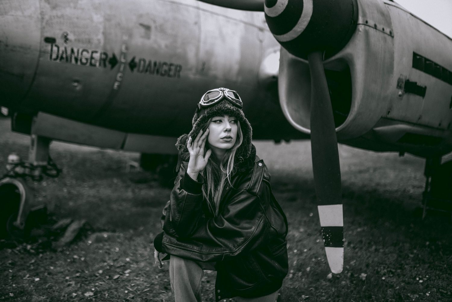 Vintage-style black and white photograph featuring an aircraft with danger warning signage.