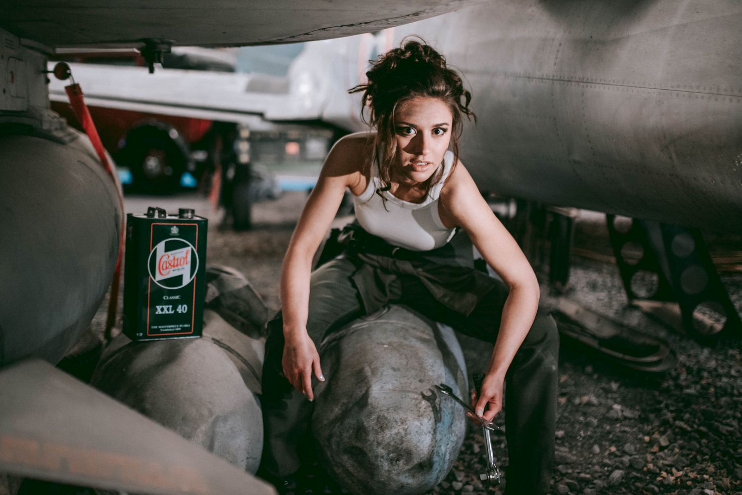 A grungy industrial photoshoot featuring a dramatic pose on mechanical equipment.