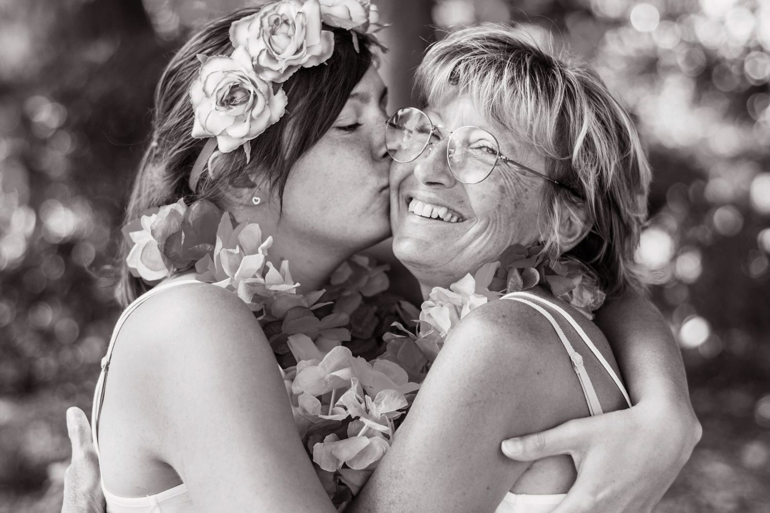 Black and white close-up of friends sharing an intimate moment outdoors.