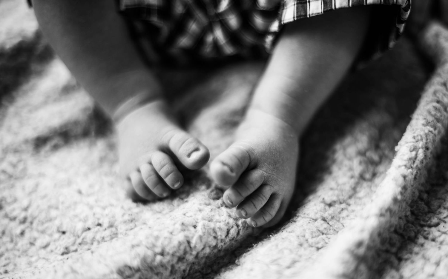 Series of monochrome images showing delicate baby hands and feet against a soft surface.