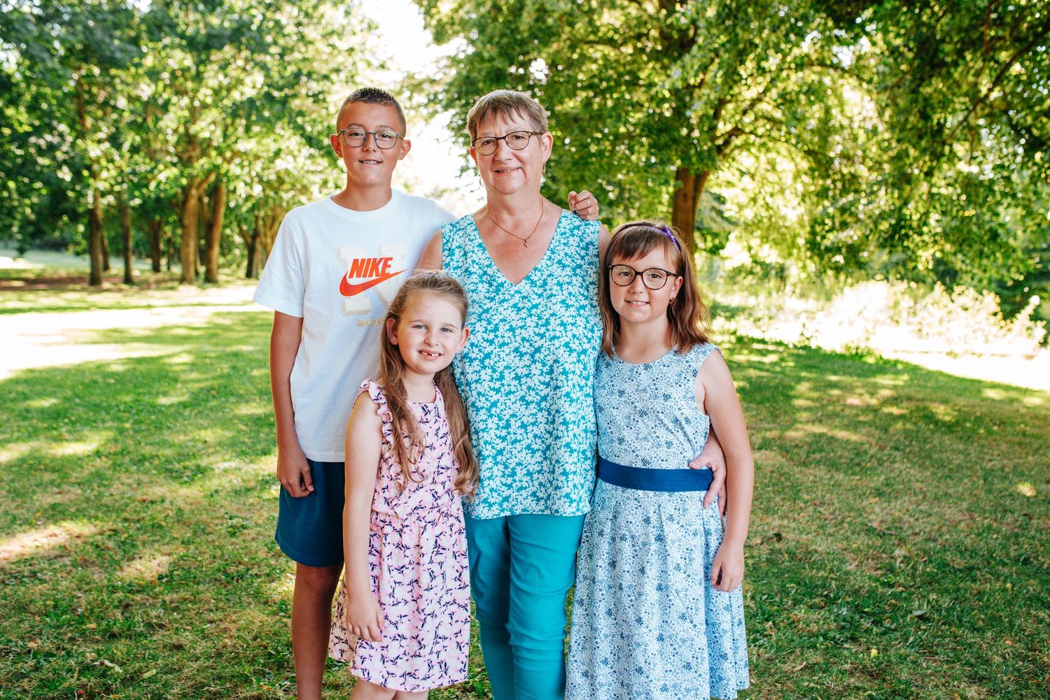 Family members in coordinated blue and floral outfits posing together in sunny garden setting.