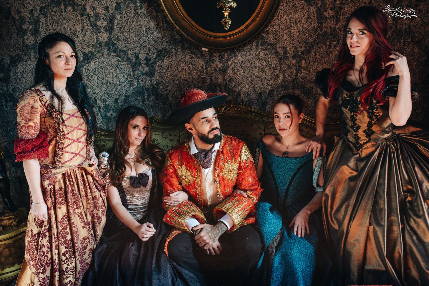Victorian-style group portrait in dark, ornate setting with dramatic period costumes.